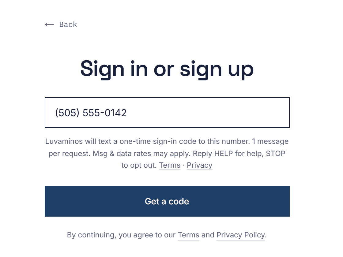 The Luvaminos sign-in screen on a computer, with a mobile number typed in the box and the text-message notice shown under it